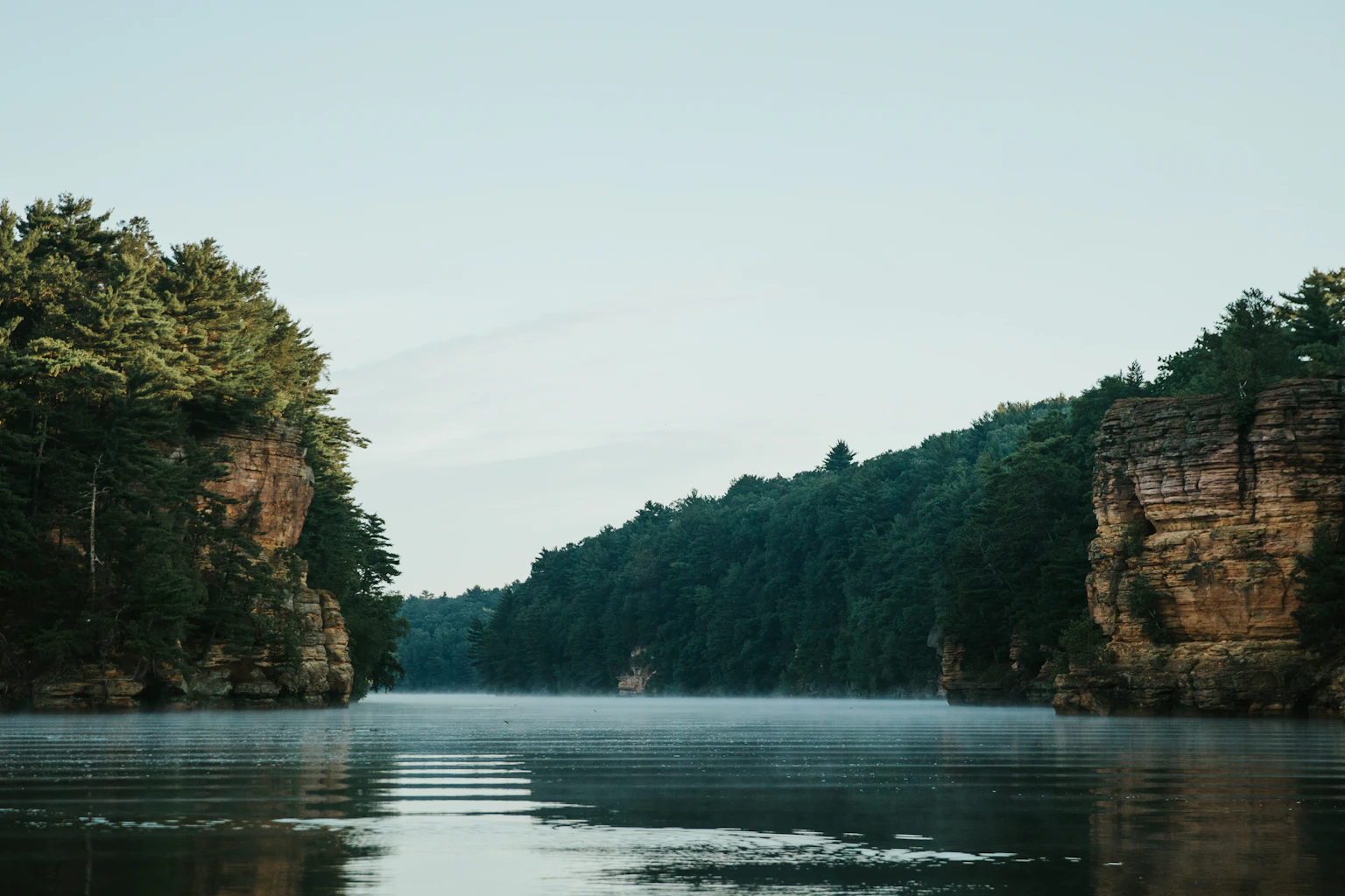 The Wisconsin River winding between wooded sandstone cliffs in Wisconsin Dells