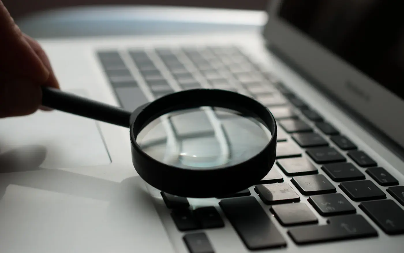 A magnifying glass held over the keyboard of a laptop